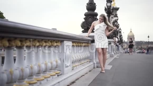 迷人的金发女孩站在桥上穿着白色时尚的裙子在大城市的背景下行动性感加上尺寸模型视频的预览图