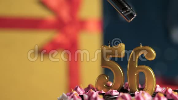 生日蛋糕数字56金色蜡烛用打火机点燃蓝色背景礼品黄色盒子用红丝带系好视频的预览图