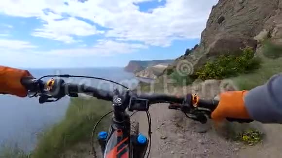 从行动相机电动自行车车把和手同时骑在悬崖边缘沿海骑自行车的人手牵手视频的预览图