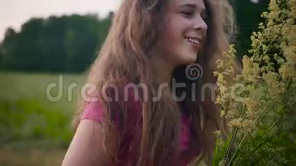 一个金发碧眼的年轻姑娘手里拿着黄色手里拿着黄色的野花动作缓慢视频的预览图