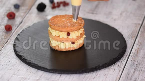 糕点厨师用奶油和浆果制作法国米尔菲耶法式甜点牛奶酥皮点心和奶油冻视频的预览图