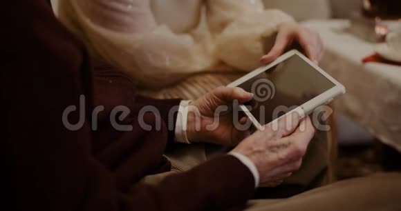 孙女和祖父在家讨论数码平板电脑视频的预览图