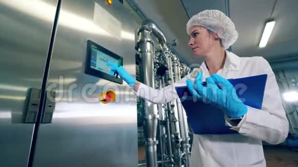 工厂工人检查一台机器在显示器上打字女职工控制生产设备质量视频的预览图