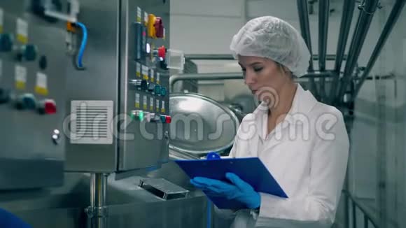 女职工控制生产设备质量一名妇女在乳品厂检查机器视频的预览图