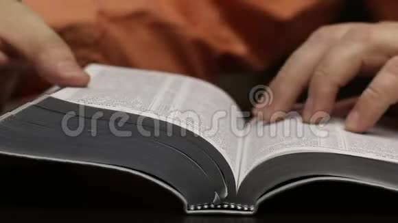 桌子上放着一本公开的圣经这个人迅速翻页寻找想要的章节阅读引导手指沿着视频的预览图
