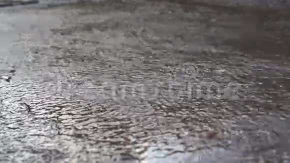 一股雨水沿着沥青城市的坡路流视频的预览图