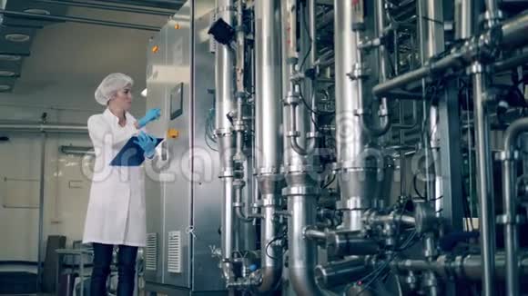 一名妇女在一家乳品厂检查油罐工厂生产线的质量控制视频的预览图