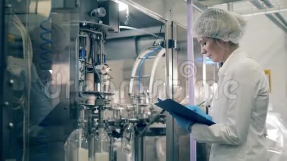 一名工人检查用牛奶灌装瓶子的机器工厂生产线的质量控制视频的预览图
