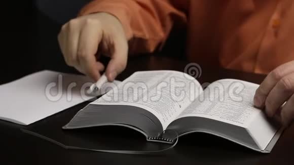 一个人坐在桌边读圣经把一根手指按在线条上把重要的思想写在一张纸上视频的预览图