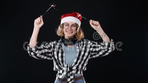 穿着黑白格子衬衫的欧洲时髦女孩脖子上戴着耳机戴着红色圣诞帽庆祝视频的预览图