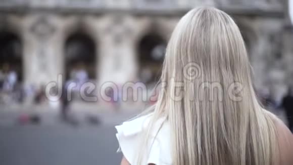 穿过历史中心美丽的女孩金发碧眼的直长发贴在古老的历史建筑上视频的预览图