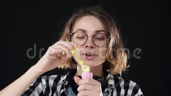 幸福情感女孩的特写肖像在黑色背景上用棍子吹了一个大肥皂泡演播室的录像视频的预览图