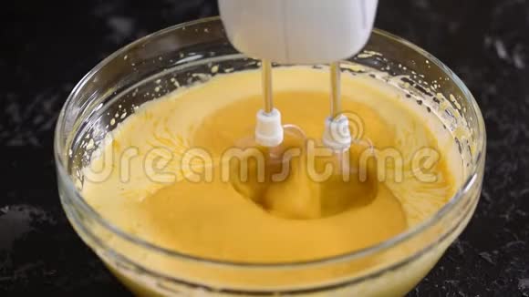 双手将面糊与搅拌器混合在玻璃碗中用面糊把面粉加入碗里视频的预览图