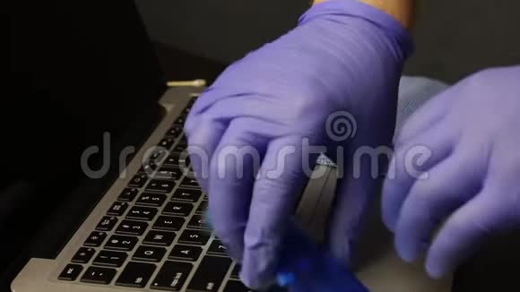 键盘上有一台笔记本电脑它是一把刷子和一张用来清洗的餐巾纸一个戴着橡胶手套的人拿着刷子和刷子视频的预览图