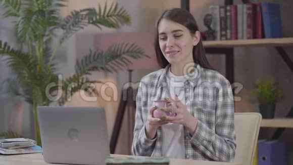 自信的高加索女人看着笔记本电脑屏幕就像坐着喝杯茶或咖啡微笑着女性视频的预览图