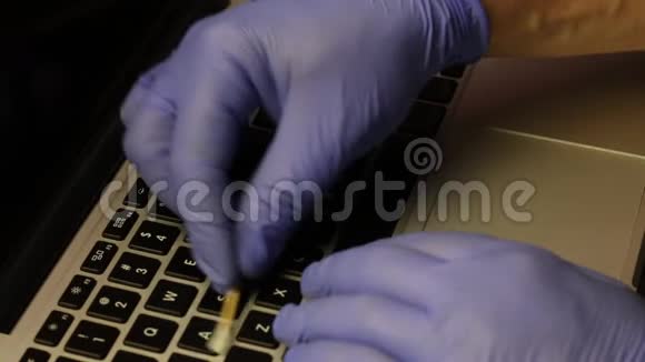 一个戴橡胶手套的人正在清洗他的笔记本电脑棉签清洁钥匙然后他用一个特殊的键盘擦拭笔记本电脑键盘视频的预览图