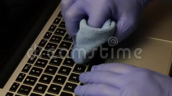 一个戴橡胶手套的人正在清洗他的笔记本电脑他用一张特殊的餐巾纸擦拭笔记本电脑键盘保护工作设备视频的预览图