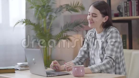 正面白种人黑发女孩的肖像看着笔记本电脑屏幕摇头是的青年专业人员视频的预览图