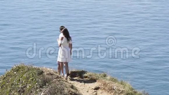 年轻幸福的恋人在陡峭的斜坡上蓝色的涟漪背景行动年轻夫妇站在岩石上视频的预览图