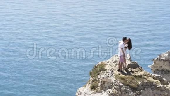 情侣在海边接吻站在碧波荡漾的水面上行动在海上旅行的男孩和女孩视频的预览图