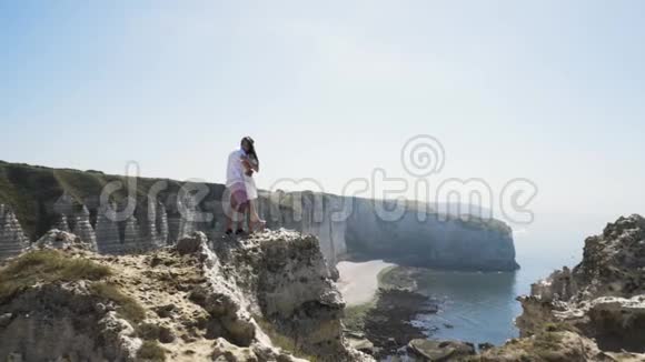 一对夫妇站在岩石上拥抱和亲吻在蓝天大海和白色悬崖上看着幸福和相爱视频的预览图