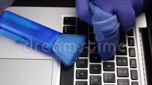 一个戴橡胶手套的人正在清洗他的笔记本电脑他用一张特殊的餐巾纸擦拭笔记本电脑键盘上的钥匙保护视频的预览图