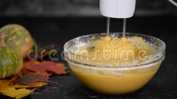 一个白色的经典搅拌机将黄色面团翻转为南瓜蛋糕视频的预览图