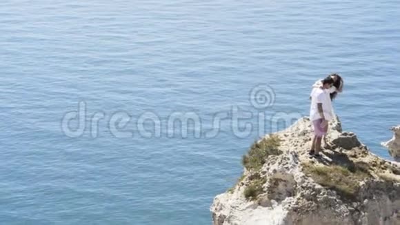 年轻幸福的恋人在陡峭的斜坡上蓝色的涟漪背景行动年轻夫妇站在岩石上视频的预览图