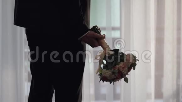 家里手里拿着结婚花束的新郎白色衬衫夹克视频的预览图