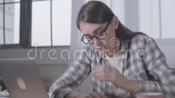 年轻的白人女孩摘下黑色眼镜把头放在笔记本电脑键盘上累了的年轻女商人视频的预览图