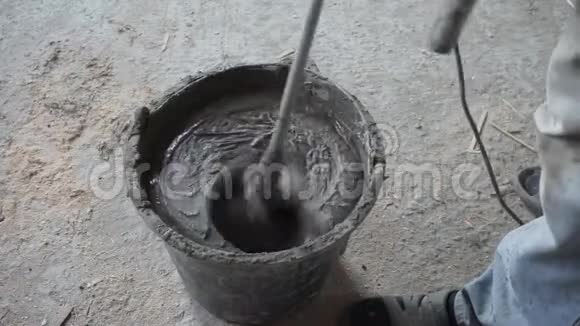 在一个黑色的小水池里搅拌水泥在桶里搅拌灰泥的工人工人将溶液混合在视频的预览图