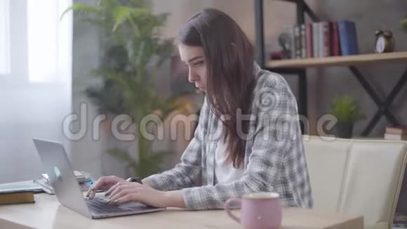 年轻的白种人商人用手提电脑键盘打字看着她的手表从事项目的女性自由职业者视频的预览图