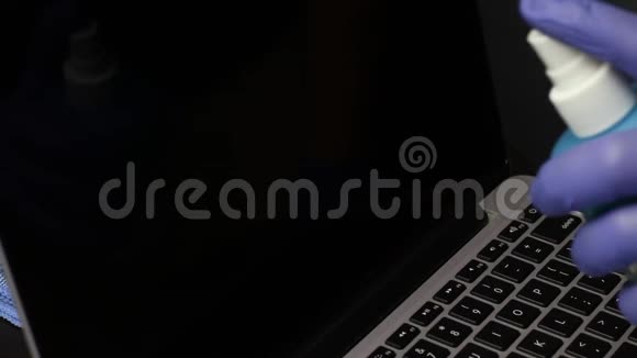 一个戴橡胶手套的男人正在清洗他的笔记本电脑一块特殊的布擦拭着笔记本电脑屏幕保护工作设备免受视频的预览图