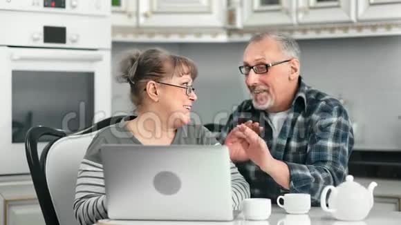 笑的老年女性看着屏幕上的笔记本享受家庭美食视频的预览图