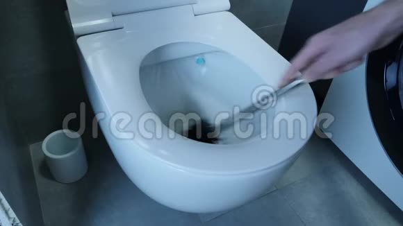 男手正用刷子清洗白色马桶近距离观看男人用海绵洗白色厕所浴室上有灰色瓷砖视频的预览图