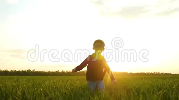 一个穿着超级英雄服装的快乐欢笑的孩子跑过一片绿色的田野或草地他的脸被光线照亮视频的预览图