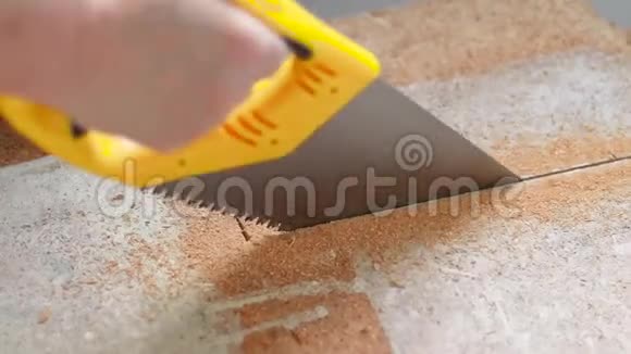 这名工人在家里用手锯锯木护盾从刨花板材料中提取的木屑视频的预览图