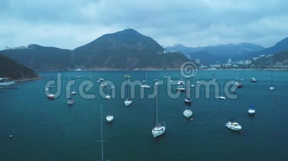 鸟瞰海湾中的白色游艇远处的山脉和城市视频的预览图