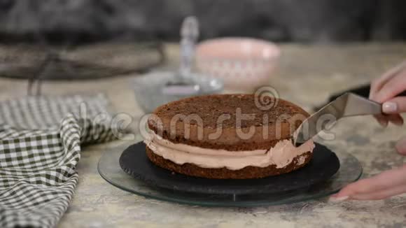 面包师在单层巧克力蛋糕的侧面涂上糖霜视频的预览图