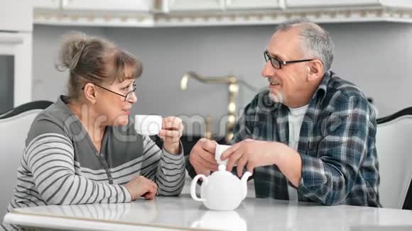 微笑的中年人在白色厨房享受咖啡休息时的友好交谈视频的预览图
