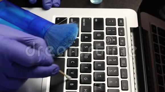 一个戴橡胶手套的人正在清洗他的笔记本电脑棉签清洁笔记本电脑键盘保护工作设备免受视频的预览图