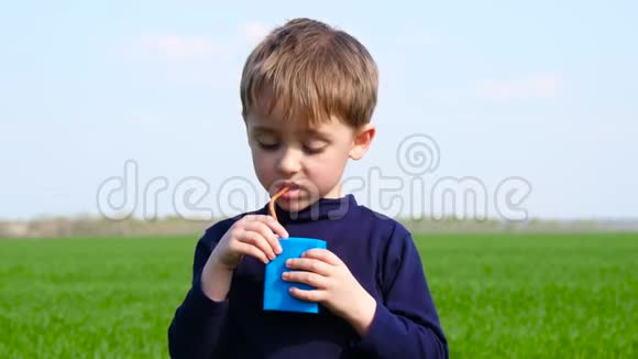 街上的一个孩子通过吸管从纸包装中喝到不好吃的果汁视频的预览图