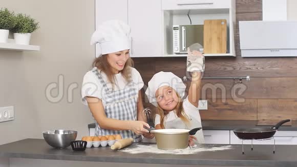 小女孩在烤蛋糕前用杯子洒面粉视频的预览图