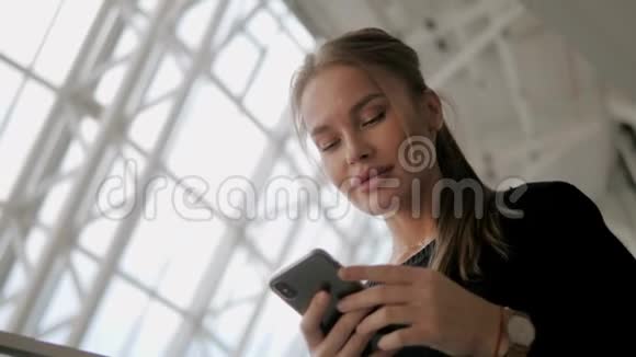迷人的金发年轻女子用智能手机拥有丰满性感的大嘴唇视频的预览图