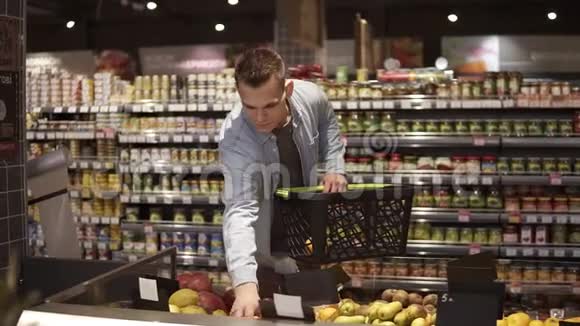 一家杂货店超市的农产品部门年轻积极的男人在买水果和蔬菜的画像视频的预览图