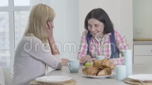 两位成年白人妇女坐在桌旁微笑的画像在家里交流的朋友友谊视频的预览图