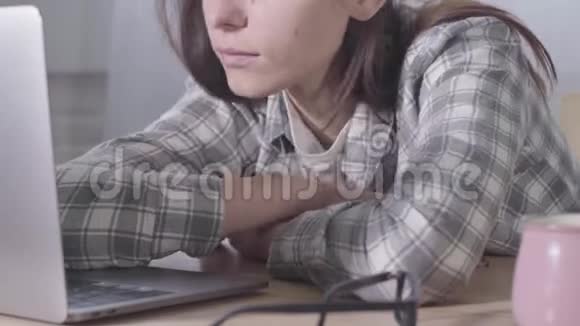 年轻的黑发白种人女孩把头放在笔记本电脑键盘上的特写精疲力竭的女商人在家辛勤工作视频的预览图
