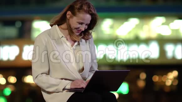 快乐的女人晚上看着外面的笔记本电脑屏幕感到兴奋视频的预览图