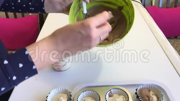 一个女人把有可可的面团放在松饼烤盘里做大理石蛋糕视频的预览图