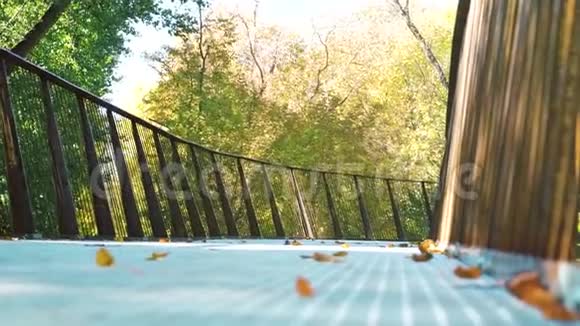 快乐的女孩在秋天公园的金属桥上慢跑视频的预览图